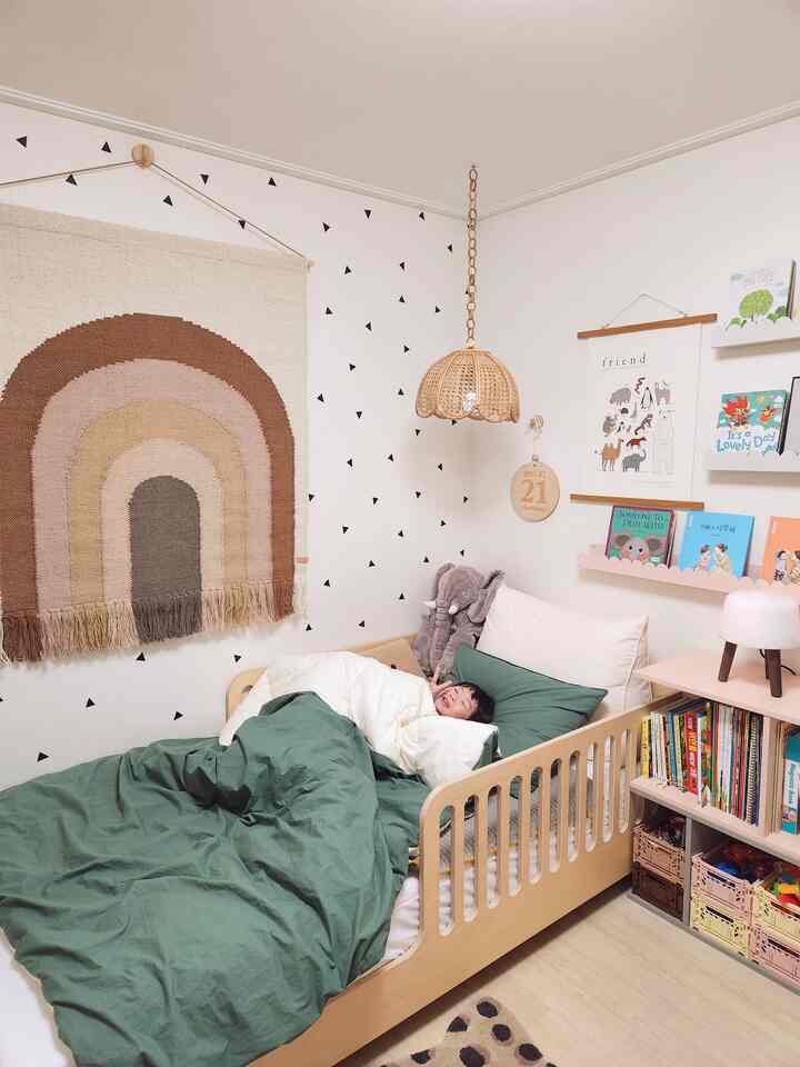 ナチュラルな木目調とグリーンの寝具が調和した子供部屋、ベッドに子供が横たわる温かみのあるインテリア