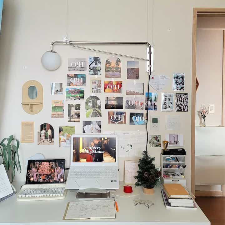 Minimal home office study with white and gray tones, featuring a clean desk and posters decorating the wall