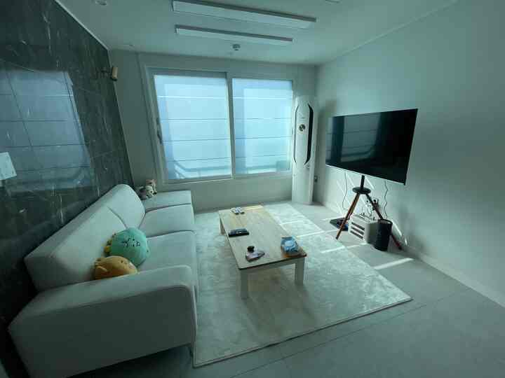 白とモダンスタイルの二人暮らし用リビング、ソファ、コーヒーテーブル、テレビが配置された落ち着いた空間