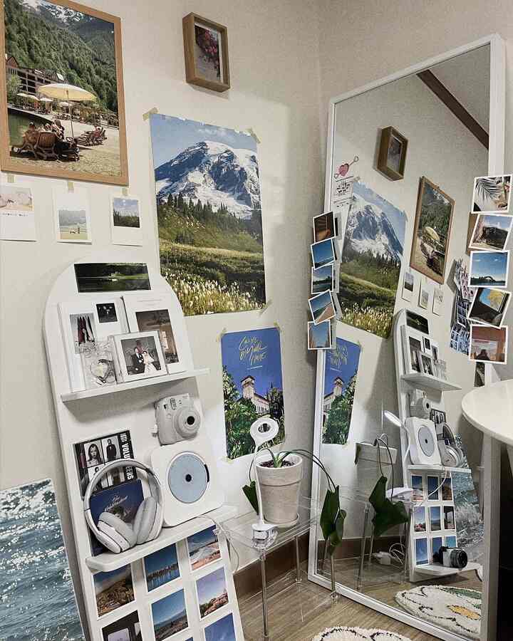 A cozy space with white walls and wood-tone flooring featuring vintage posters, photos, a large full-length mirror, and shelves creating an emotional atmosphere