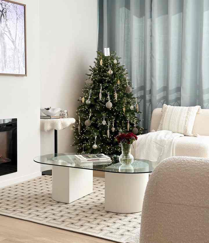 白とミント色調のリビング、クリスマスツリーと白ソファ、ガラスのコーヒーテーブルが調和する暖かな空間