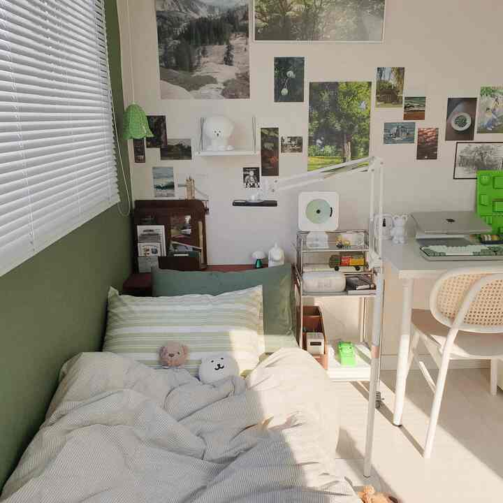 White and green toned bedroom featuring a bed, desk, and multipurpose shelf in a cozy natural modern space