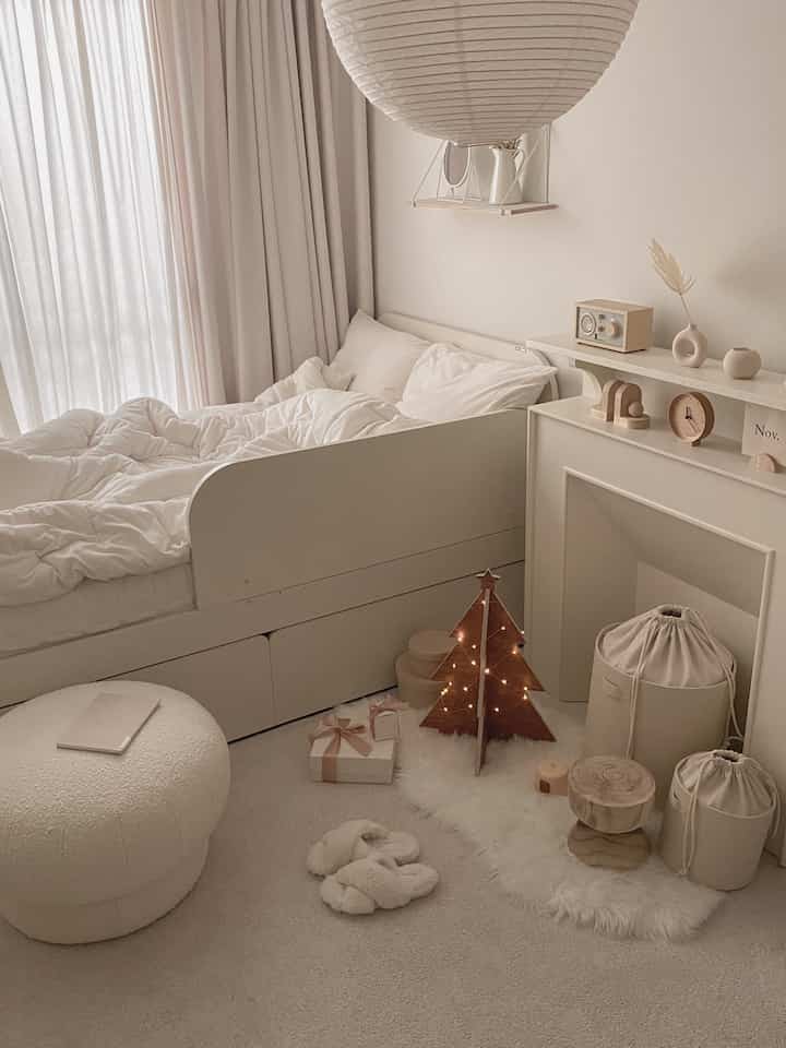 Cozy bedroom in warm white and natural tones featuring a wooden Christmas tree and plush rug creating a festive atmosphere