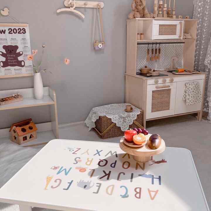 白とベージュの色調の子供部屋、ナチュラル素材の家具とアルファベットのテーブルが配置された雰囲気のある空間