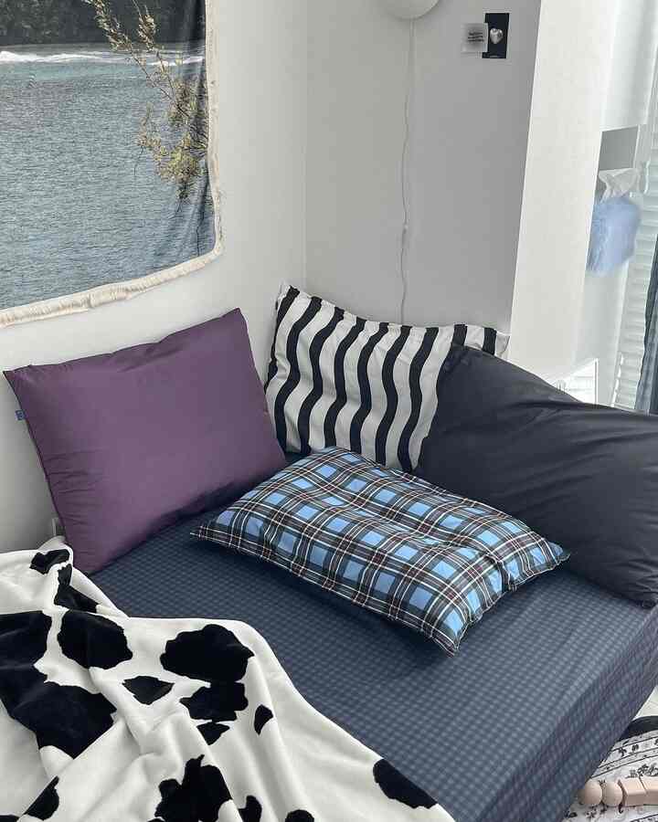 Black and blue toned bedroom featuring checkered pillows and a sofa bed creating a cozy atmosphere