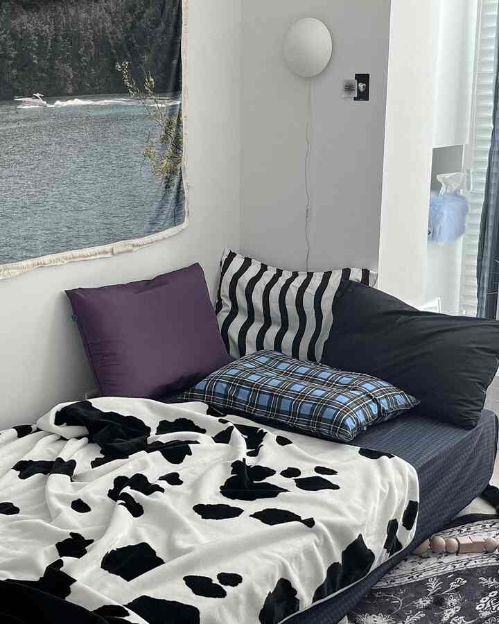 White and black themed bedroom featuring assorted pillows and a cow print blanket, creating a tidy and cozy space