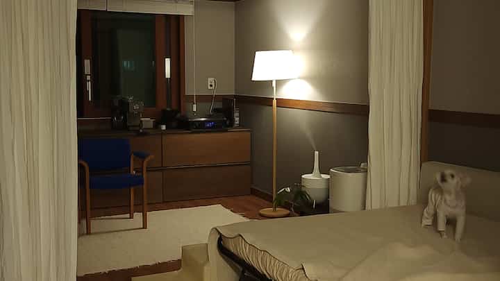 Beige and wood tone living room featuring sofa, a dog, and floor lamp with cozy atmosphere