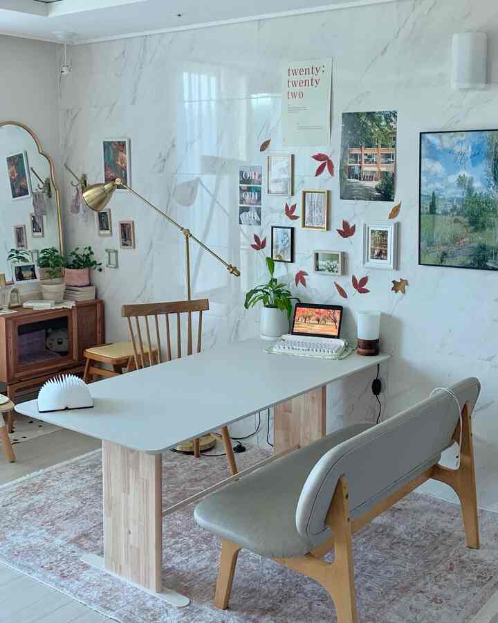 A cozy living and dining room in white and wood tones featuring autumn wall decor and a modern dining table set
