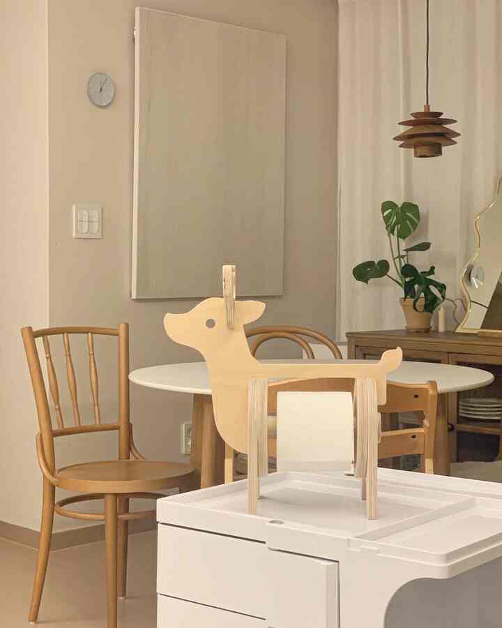 Natural tone simple dining room featuring wood furniture, a white dining table, chairs, and a potted plant creating a cozy atmosphere