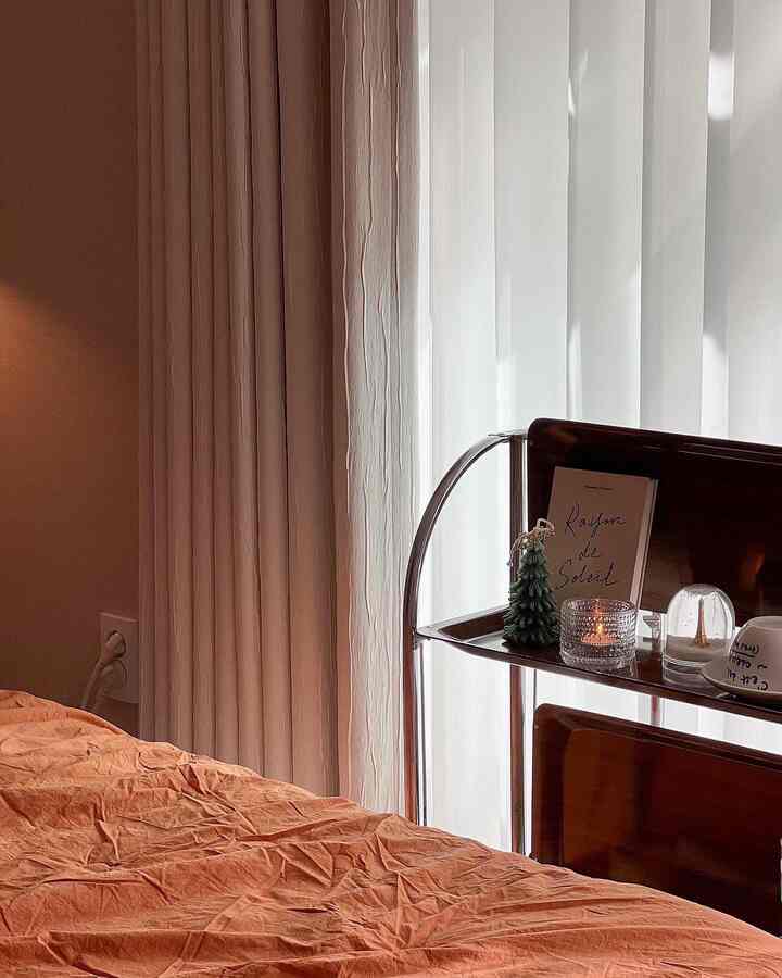 Beige and brown toned bedroom featuring orange bedding and a vintage trolley emitting a warm, cozy atmosphere