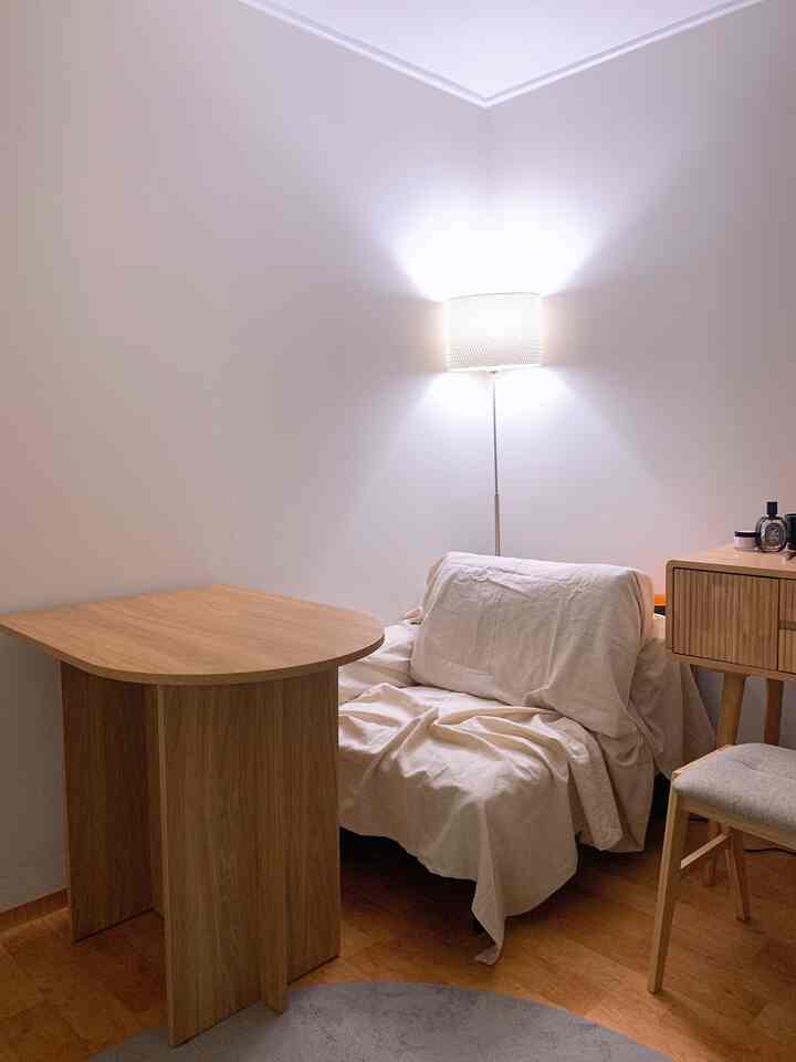 Natural wood-tone and ivory colored bedroom featuring a semi-oval table and sofa creating a cozy home cafe atmosphere