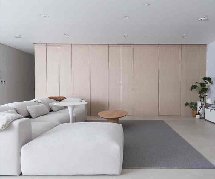 Bright ivory and wood tone living room featuring minimal sofa, round tables, and large sisal look rug creating a calm atmosphere