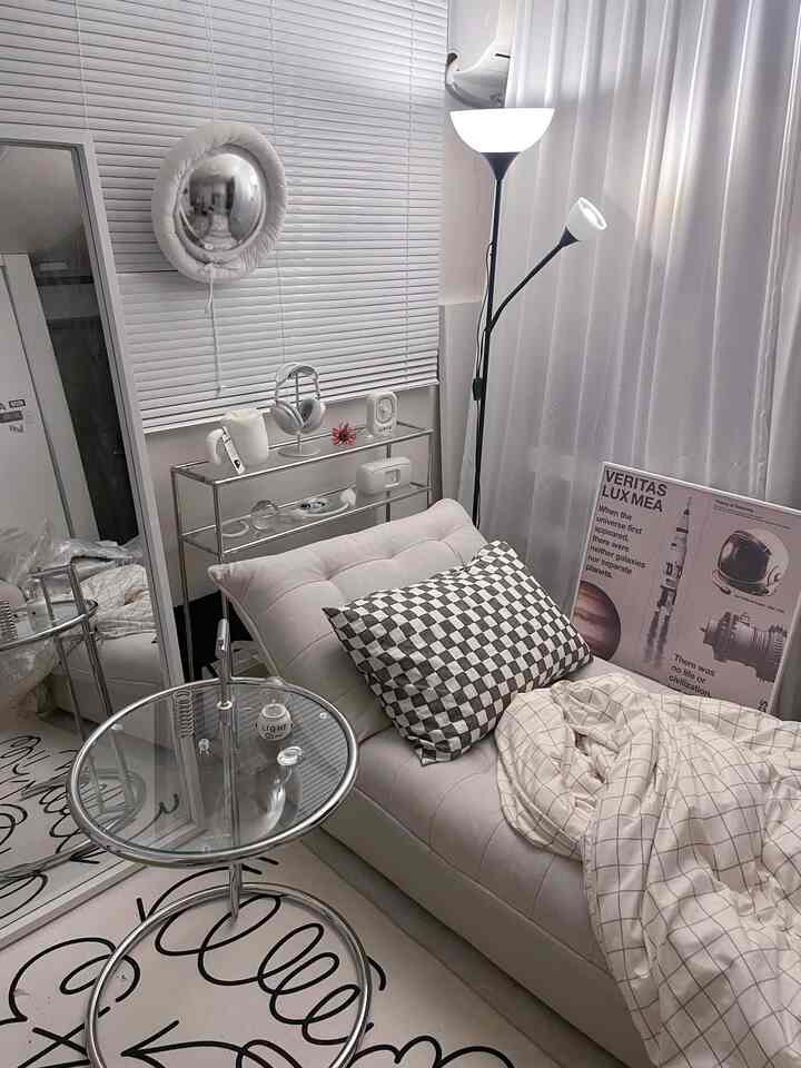 白とベージュのトーンの一人暮らしの部屋、ソファベッドとサイドテーブル、白いカーテンとブラインドが調和した現代的で落ち着いた雰囲気のインテリア