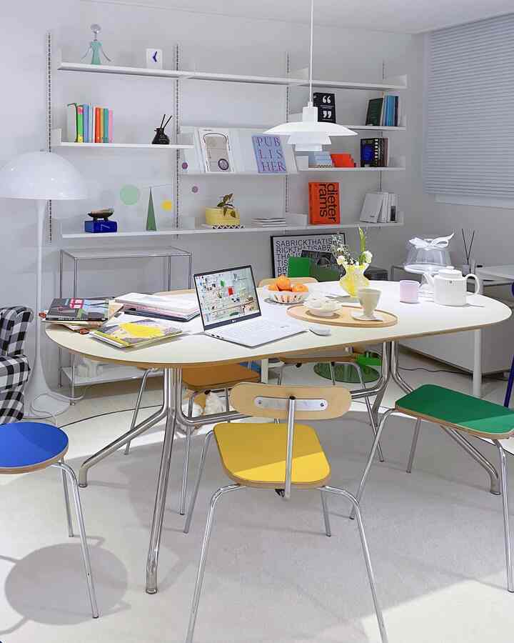 Modern and bright home office and dining space with dominant white tone and yellow and green accent chairs