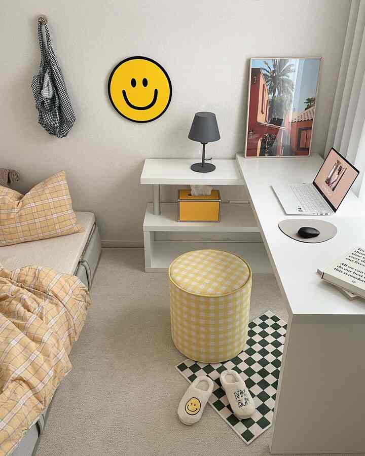 Yellow and white tone bedroom and home office featuring laptop, stool, and simple warm decor