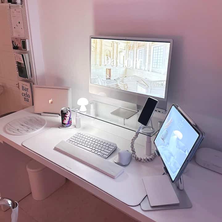 Minimal white-toned home office featuring a monitor and tablet on a clean desk setup