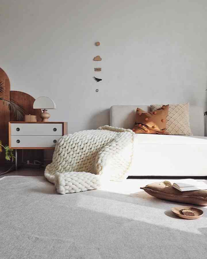 A white and brown toned living room featuring a natural modern sofa, nightstand, and rug with a cozy atmosphere
