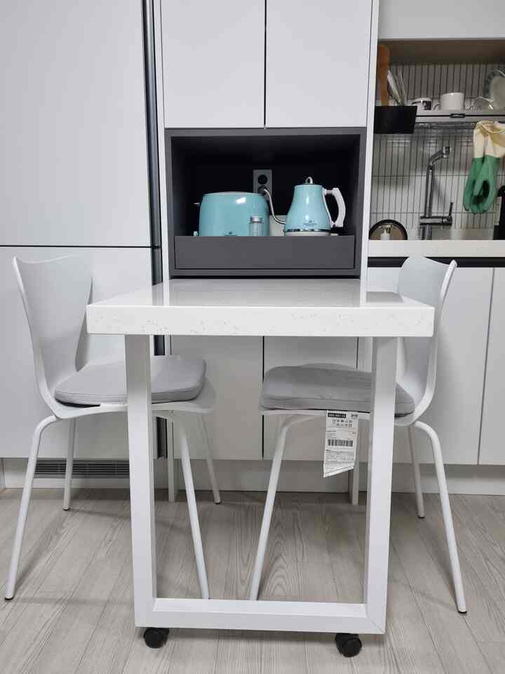 白とミント色の調和が美しいキッチン、ミント色の家電と白いダイニングテーブルと椅子が配置されたシンプルでモダンな空間