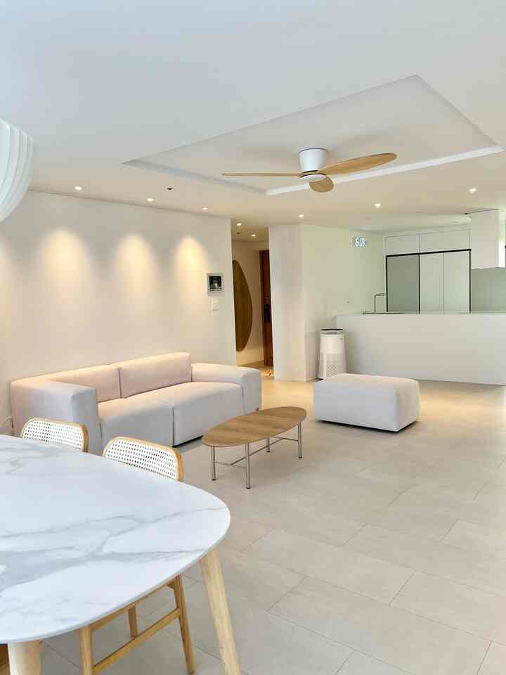 A simple modern living room and kitchen space featuring white and wood tone harmony with minimal furniture