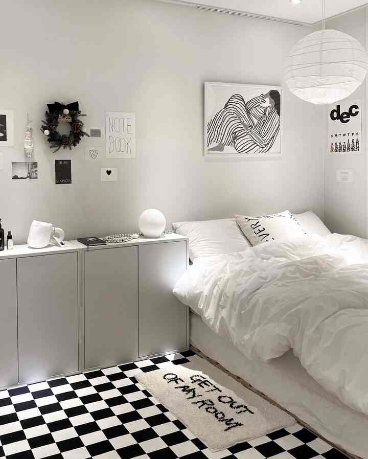 Monotone white and black bedroom featuring a neat bed and storage cabinet in a modern, simple space