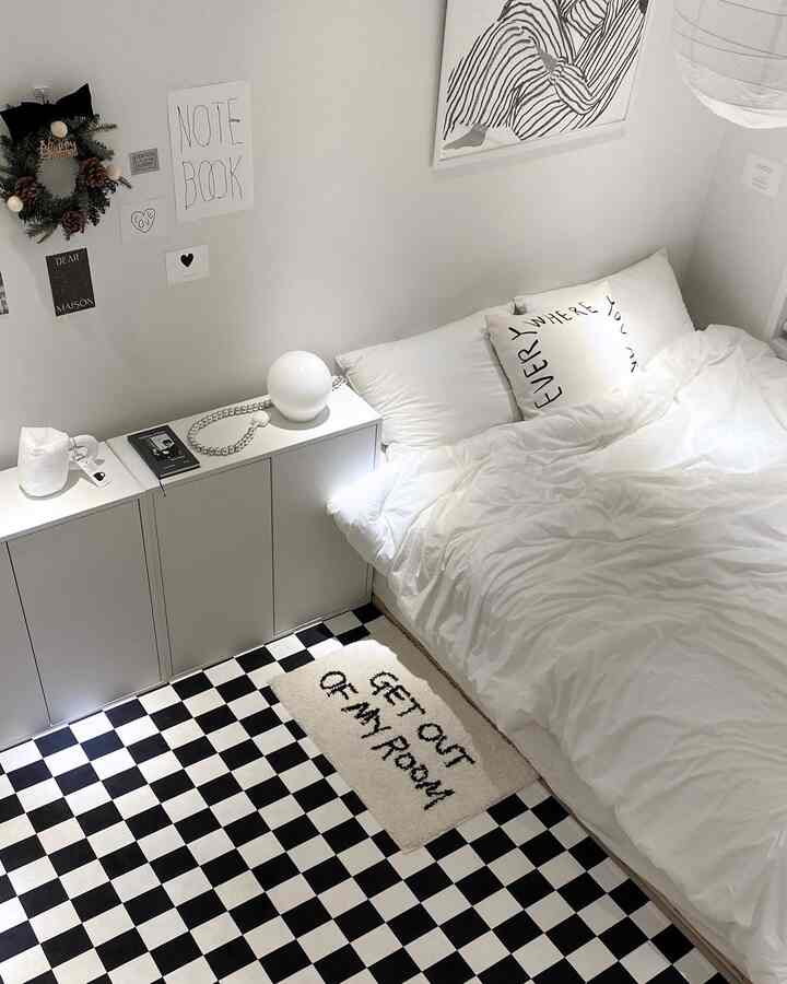 Monochrome white and black bedroom featuring a neatly made bed and checkered floor rug in a simple modern style