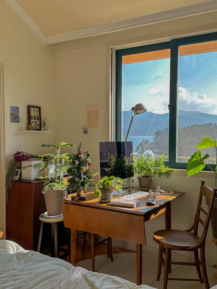 Natural toned studio home office featuring a vintage walnut desk with plants creating a cozy atmosphere
