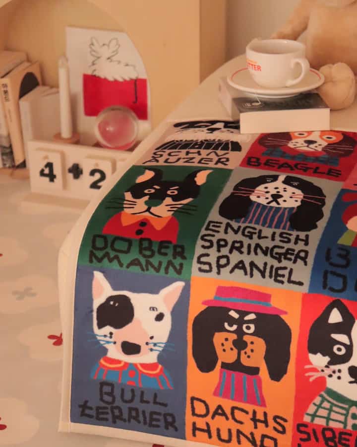 Warm beige-toned interior featuring a dog illustrated blanket and coffee cup, creating a cozy home cafe atmosphere