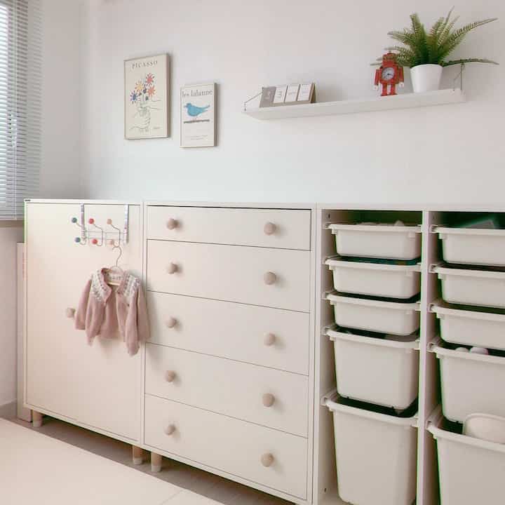 White and natural toned kids' room featuring multiple storage cabinets and neatly arranged toy bins with a clean atmosphere