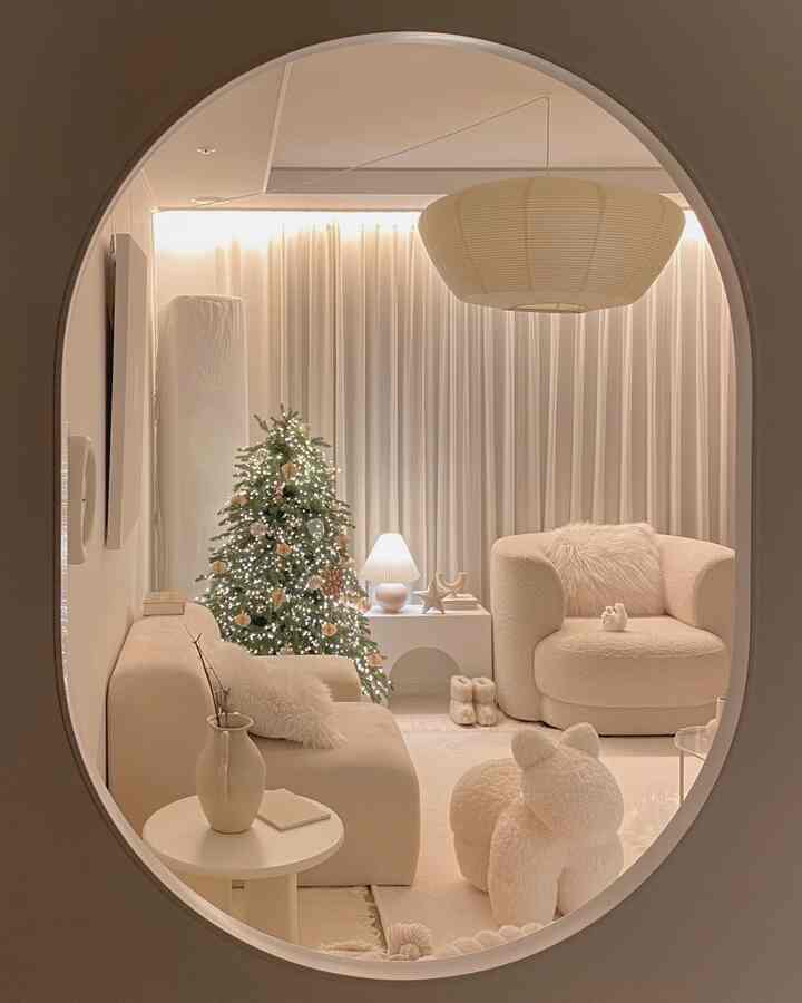 温かみのあるアイボリー調のリビング、ソファとアームチェア、クリスマスツリーとムード照明が配置された居心地の良い空間