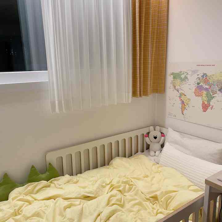 Yellow-toned kids' room featuring a yellow bedding, checked yellow curtain, and a world map poster in a natural styled space