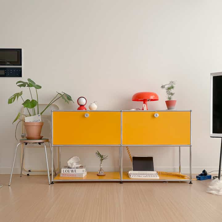 A simple and modern living room with white walls and a yellow storage cabinet