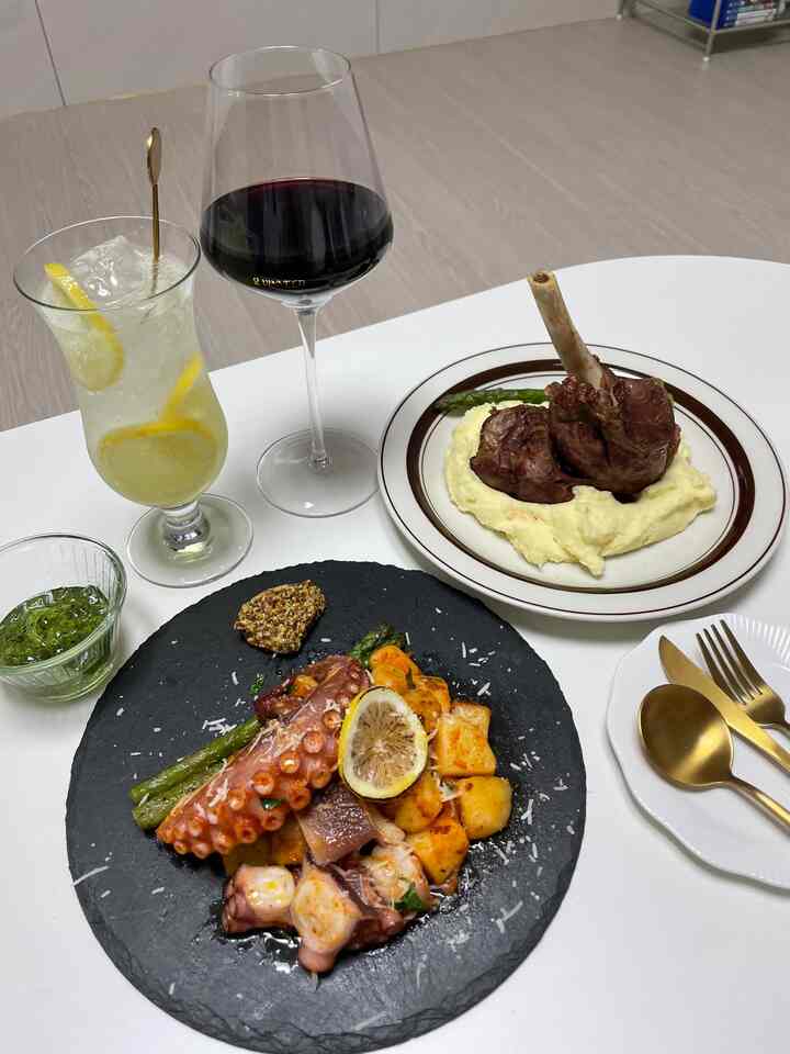 A white dining room with glass goblet and slate plate featuring plated food on a clean table setting