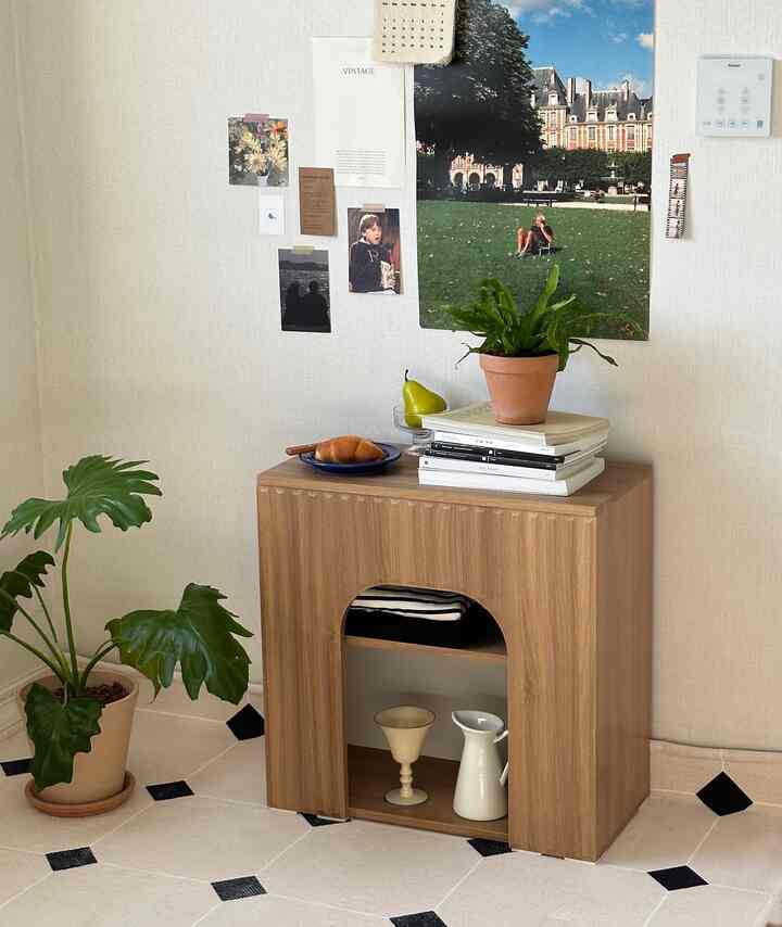 Natural wood tone and beige background living space featuring a mini wall fireplace-style cabinet with plants and decorative objects in a cozy ambiance