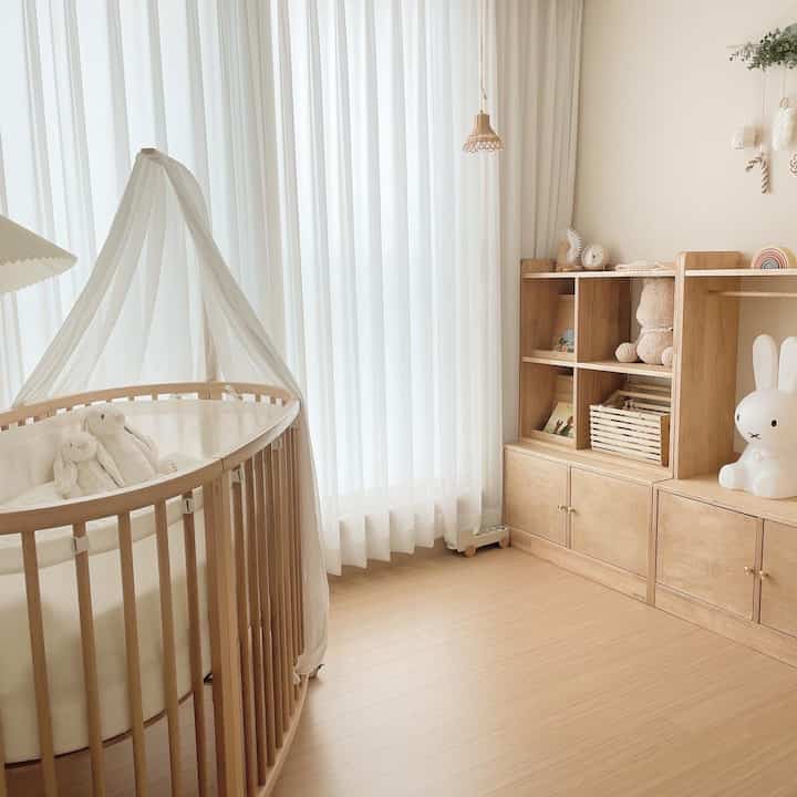 ナチュラルな色調の子供部屋、ベビーベッドと木製収納が配置されたシンプルで温かみのあるインテリア