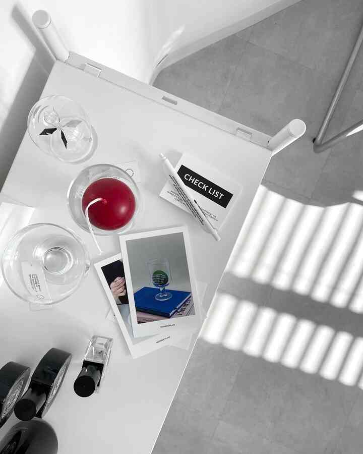 White and gray toned small room featuring a white table with a red round candle and clear glass cups in a mid-century modern style