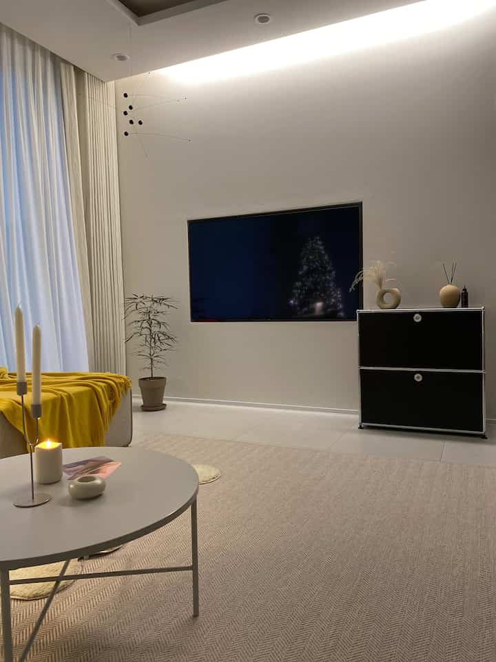 Modern living room in beige and black tones featuring modular sofa, curtains, and candles in a cozy setting