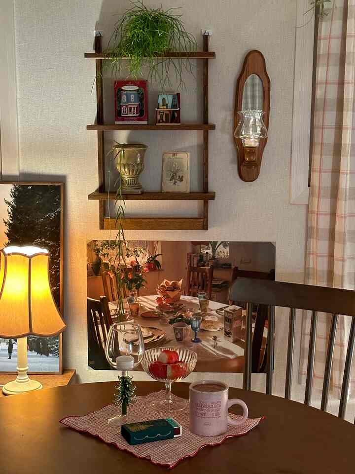 Warm brown-toned studio apartment featuring a wooden round table and chair, wall shelf and sconce light creating a cozy night mood