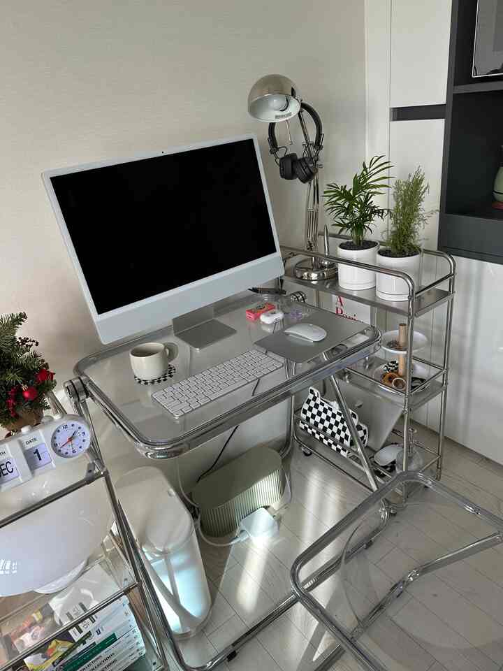 Modern home office space with transparent acrylic and silver metal materials, featuring an iMac and plants in a clean setup