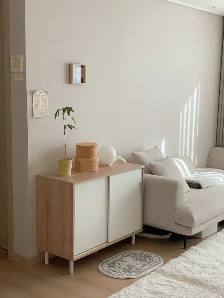 Bright wood and white toned living room featuring a sliding cabinet and ivory sofa with a clean natural modern style