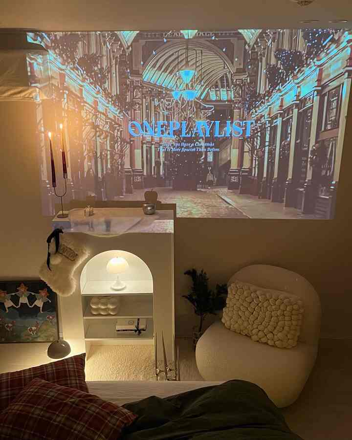 Cozy bedroom space in warm white and brown tones featuring a fireplace console and home cinema projector screen