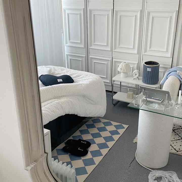 白を基調とした寝室、ネイビーのクッションとラグが配置された清潔感のあるナチュラルモダンな雰囲気のインテリア