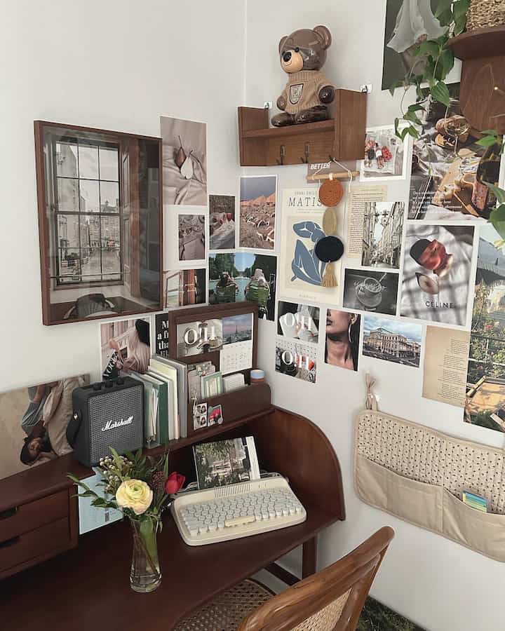 ナチュラルな木目調の机と棚が配置された落ち着いたホームオフィス空間、壁にポスターや写真が飾られた雰囲気のあるインテリア