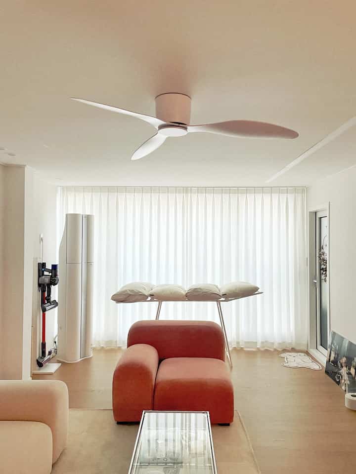 Bright white-toned living room featuring a pink sofa with pillows and neat modern decor