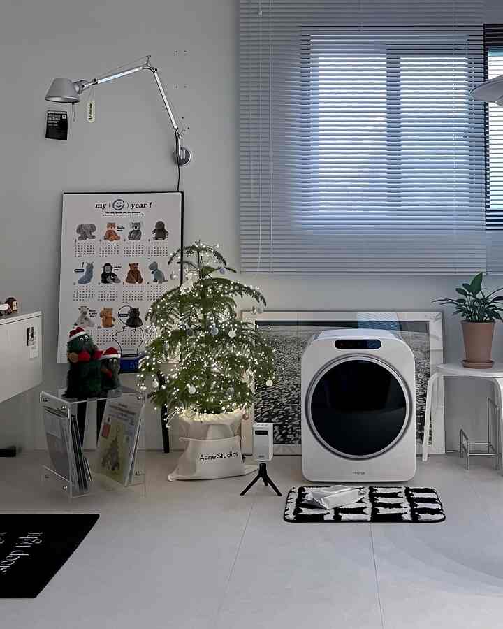 ホワイトとブラックのモノトーンのリビング、アルミブラインドと植物が配置された清潔感のあるインテリア空間