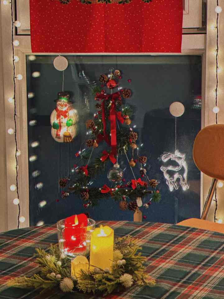 赤と緑の色調が際立つダイニングルーム、壁ツリーと輝くオーナメント、キャンドル装飾が温かみのある雰囲気を作り出す空間