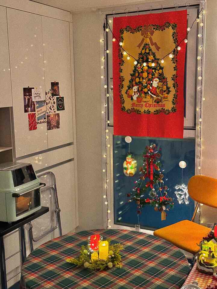 Warm red and orange-toned dining room featuring Christmas fabric poster and decorations creating a cozy atmosphere