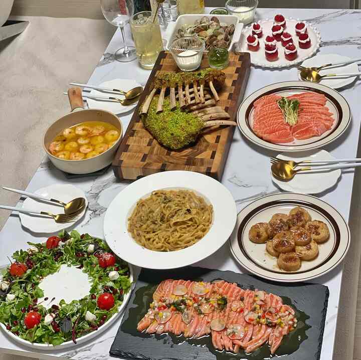 白を基調としたダイニングルームに、クリスマスのホームパーティー料理とゴールドの食器が配置された雰囲気のある空間