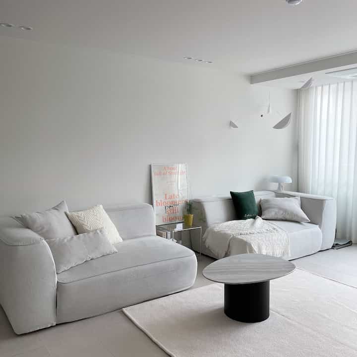 明るいホワイトとアイボリーの色調のリビング、モジュールソファと丸いコーヒーテーブルが配置されたシンプルなモダンインテリア