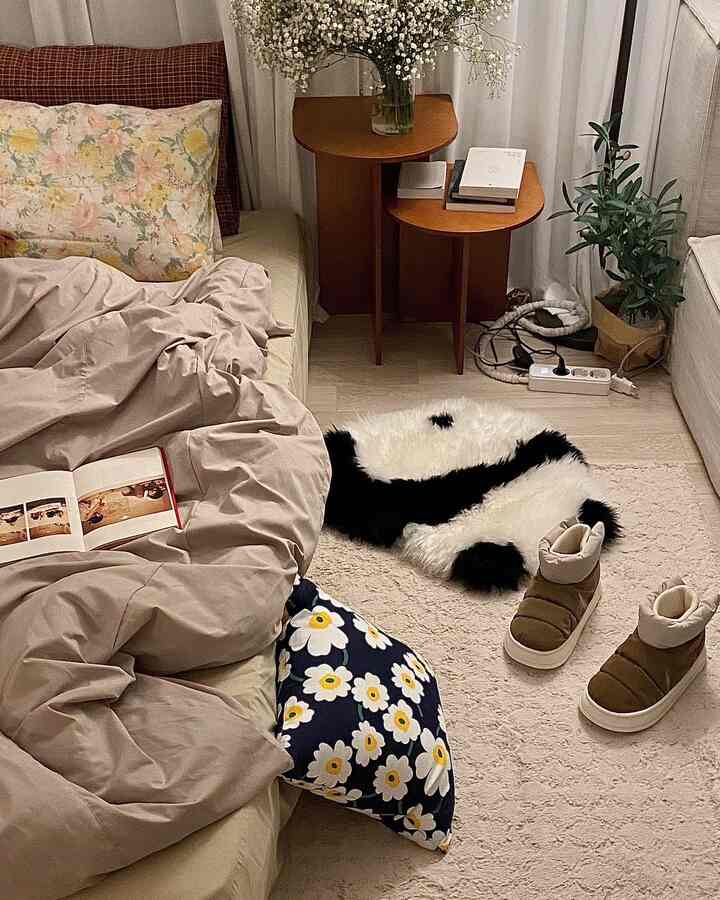 A beige and ivory toned 6-tatami bedroom featuring a bed, wooden nightstands, rugs, and plants in a cozy interior