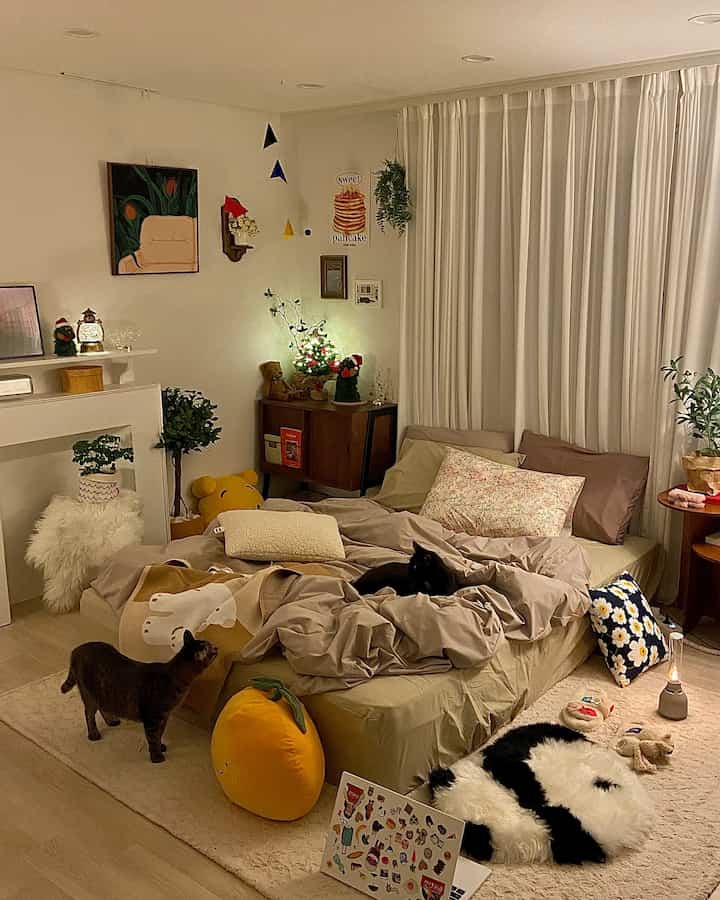 Natural beige-toned bedroom featuring a bed with pillows and duvet, white curtains, and two cats creating a cozy atmosphere